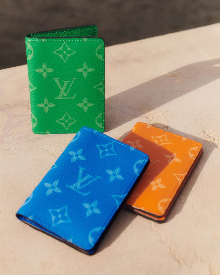 Three luxury Louis Vuitton men's wallets in green, blue and orange leather