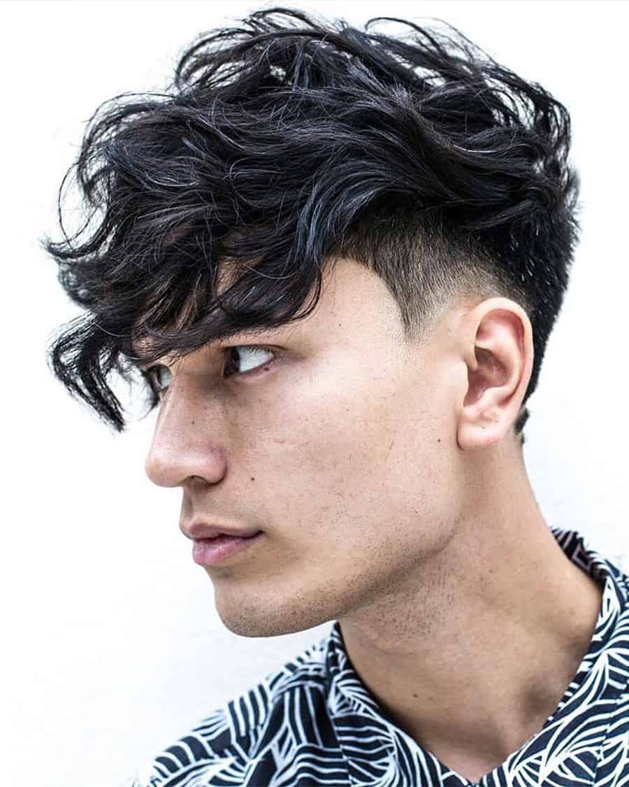 Men's long wavy hair with low taper fade and heavy fringe haircut