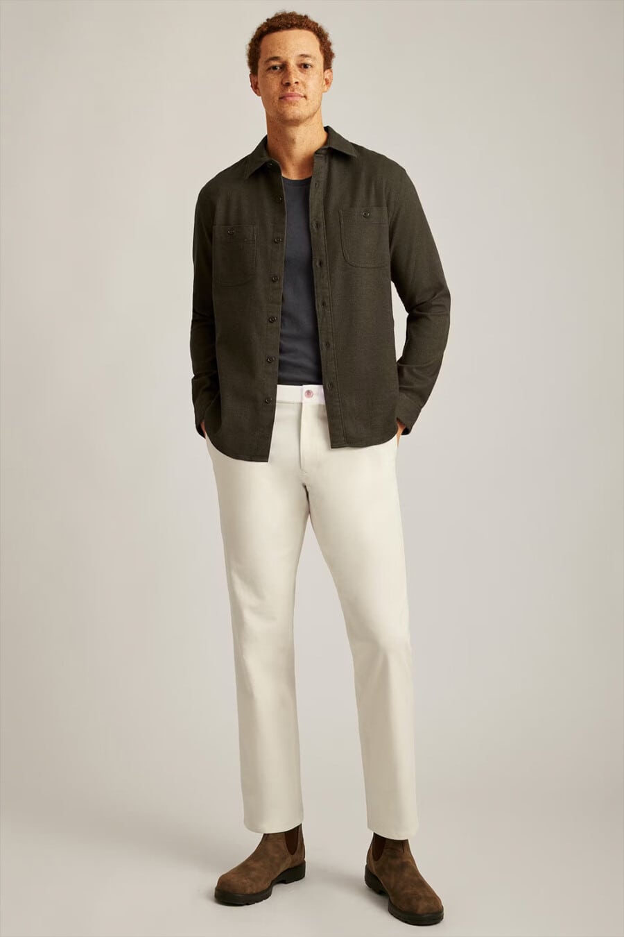 Men's cream pants, grey tucked in T-shirt, green/brown overshirt and brown suede Chelsea boots smart-casual outfit
