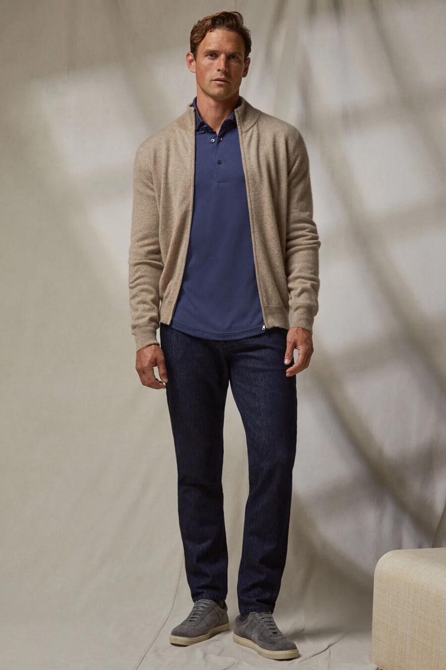 Men's dark jeans, blue polo shirt, biscuit merino zip-up cardigan and grey suede sneakers smart-casual outfit