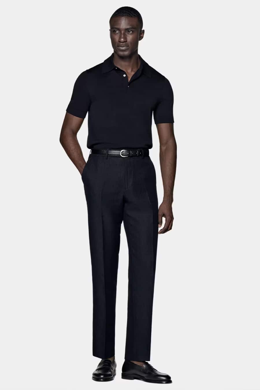 Men's black tailored pants, black tucked in polo shirt, black belt and black leather penny loafers worn sockless smart-casual outfit