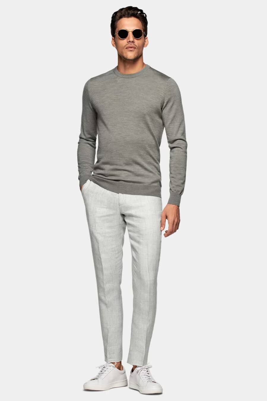 Men's light grey tailored pants worn sockless, long-sleeve grey merino wool sweater and white sneakers smart-casual outfit