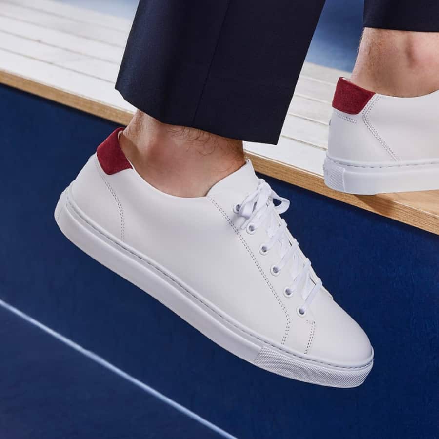 Men's white leather sneaker with red accent on heel worn with trouserds