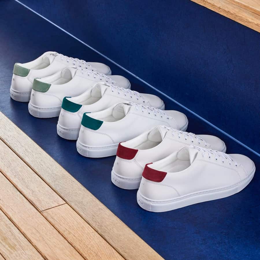 Three pairs of white leather sneakers with red, blue and green heel accents