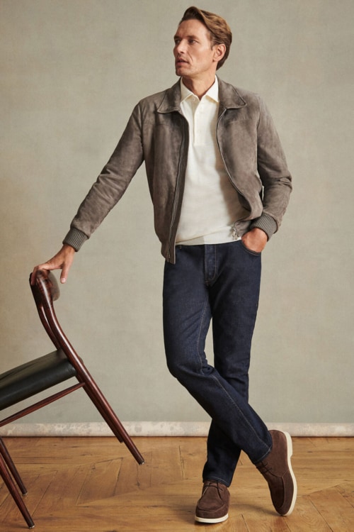 Men's dark jeans, cream polo shirt, grey suede blouson jacket and brown suede chukka boots outfit