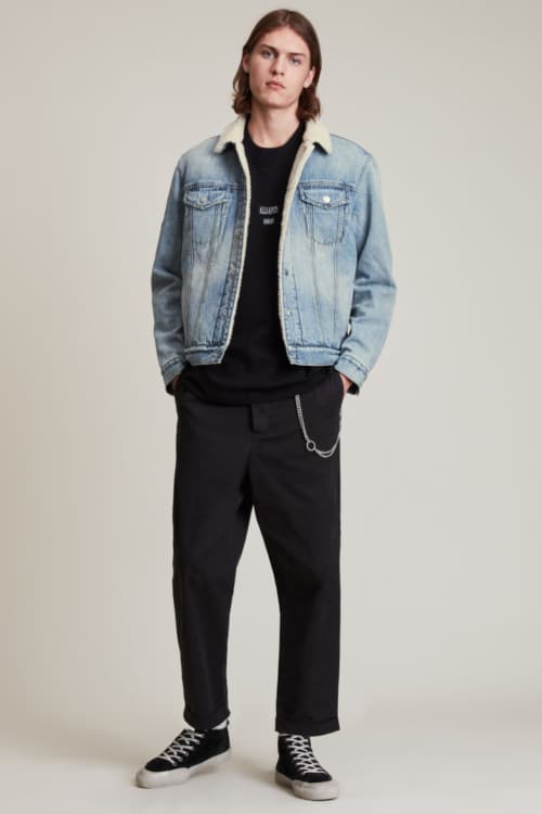 Men's wide leg, cropped black pants, black T-shirt, denim sherpa jacket and black canvas sneakers outfit