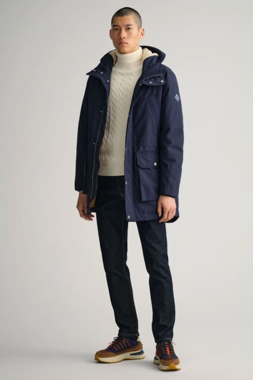 Men's blue jeans, white roll neck, navy parka and running sneakers outfit