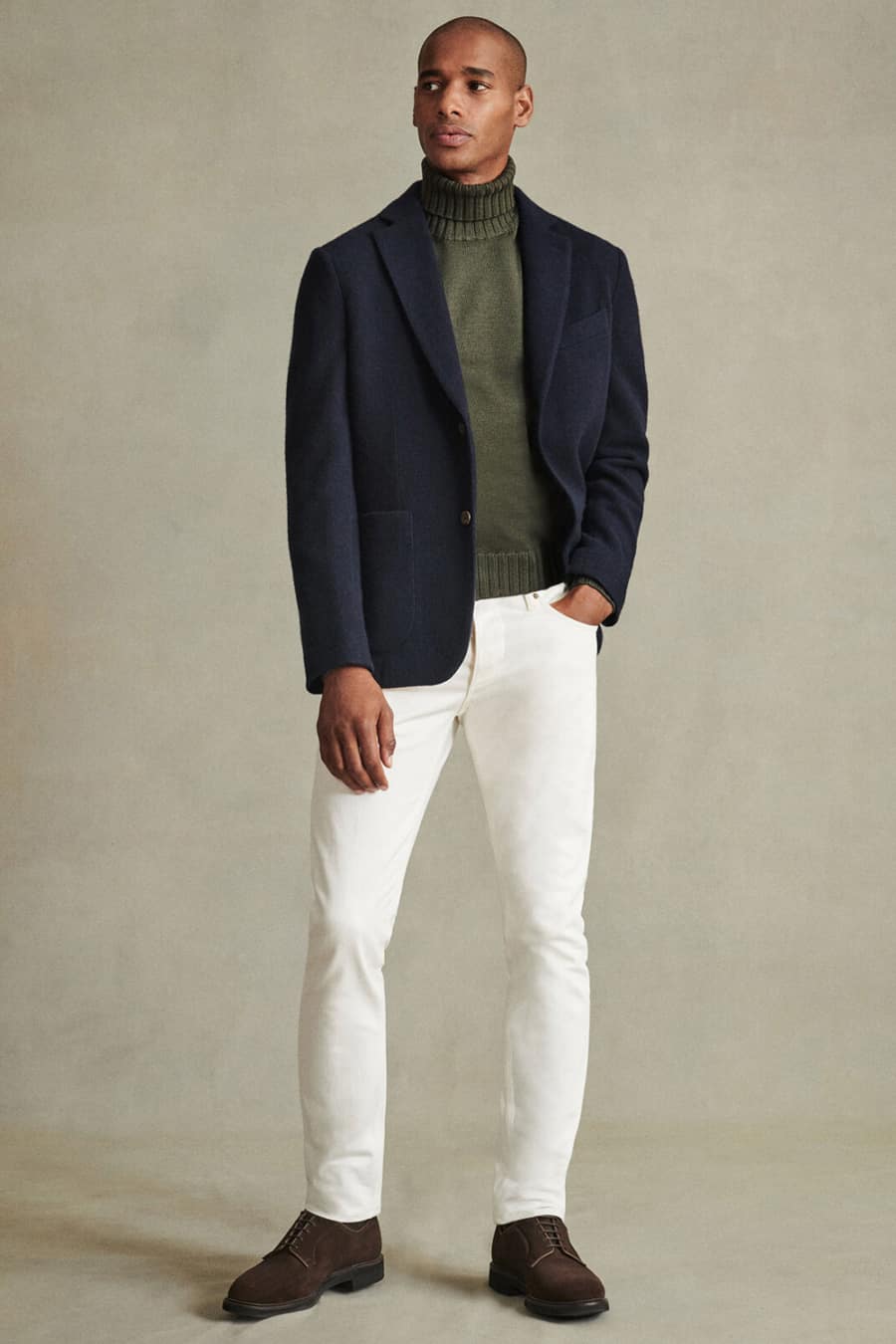 Men's white jeans, green roll neck, navy wool blazer and brown shoes outfit