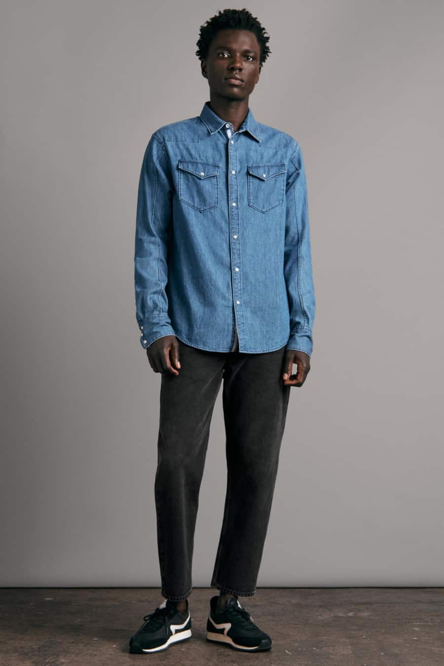 Men's black jeans, mid-blue denim western shirt and retro running shoes outfit