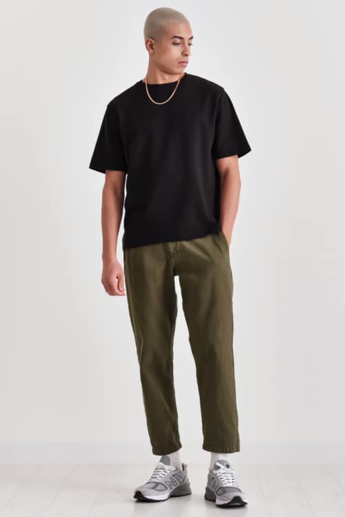 Men's cropped green pants, black T-shirt and retro running shoes outfit