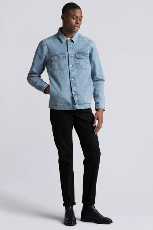 Men's double denim outfit with black jeans, light blue shirt jacket and black Chelsea boots