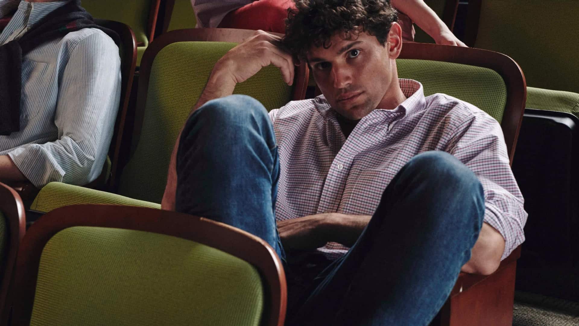 Man wearing Oxford Cloth Button Down Shirt and jeans sitting in a lecture hall