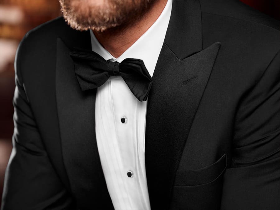Men's black tie dinner jacket worn with a traditional hand-tied black bow tie