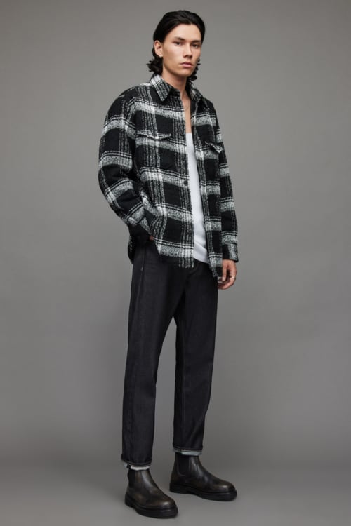 Men's raw denim jeans, white vest, black plaid flannel shirt and Chelsea boots outfit