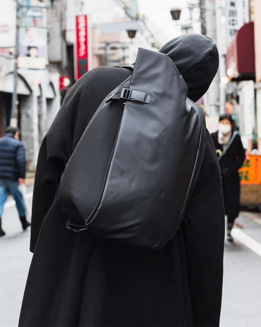Man wearing a black sculptural luxury designer backpack and black hooded jacket