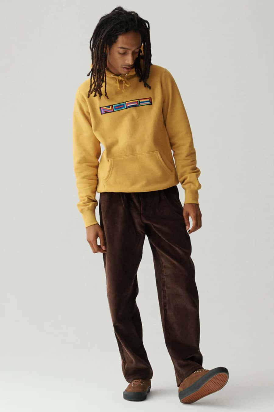 Men's brown corduroy trousers, yellow streetwear hoodie and brown sneakers outfit