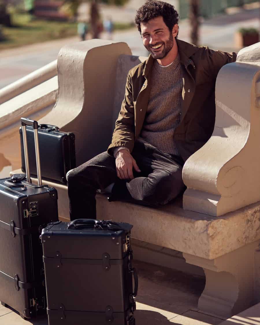 Man sitting with three luxury Steamline Luggage trunks