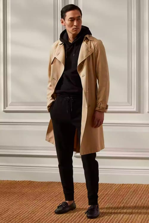 Men's black sweatpants, black hoodie, camel trench coat and black loafers outfit