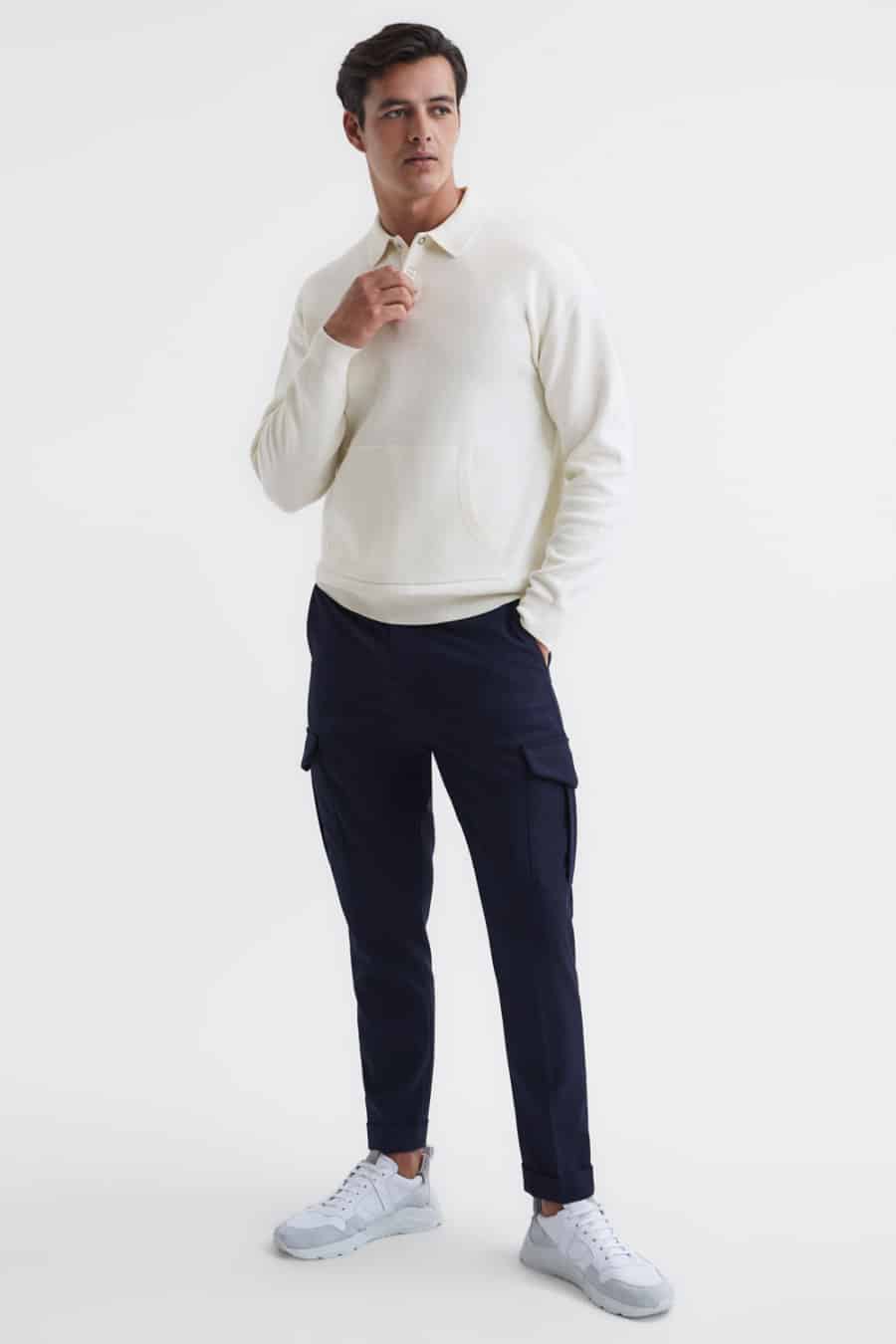 Men's navy cargo pants, white long sleeve polo shirt and white sneakers outfit