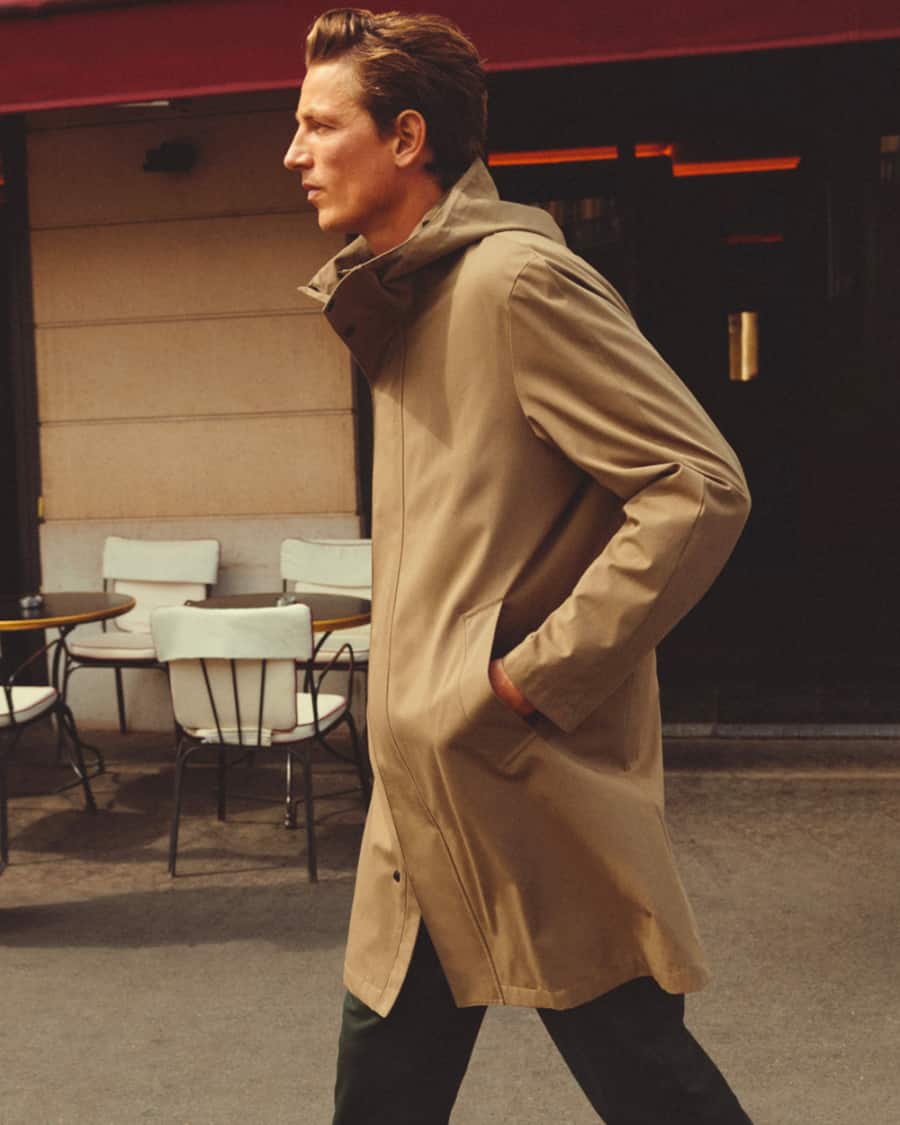 Man walking along the street wearing a waterproof mac coat in Fall
