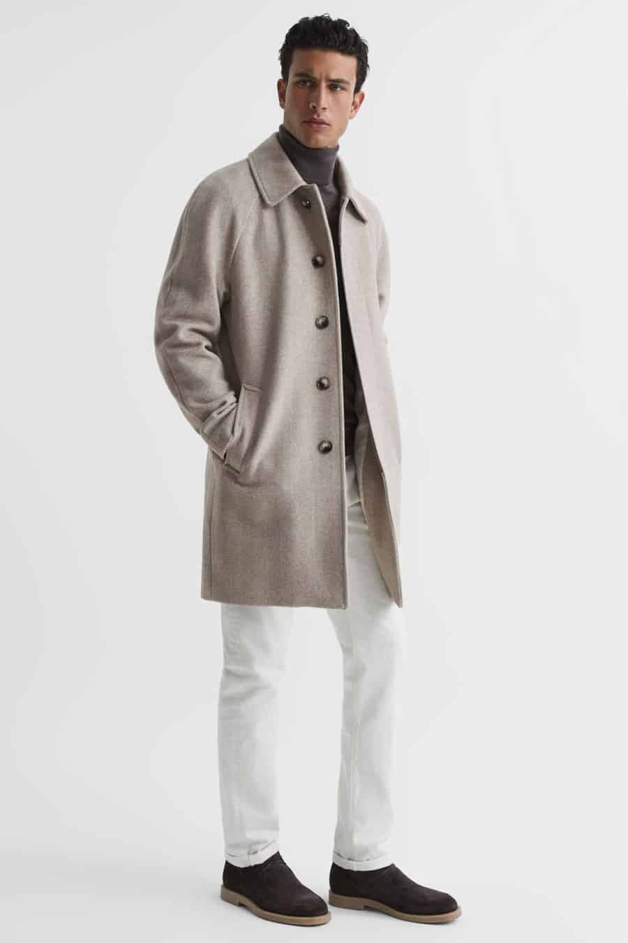 Men's white jeans, grey roll neck, beige overcoat and brown suede boots outfit