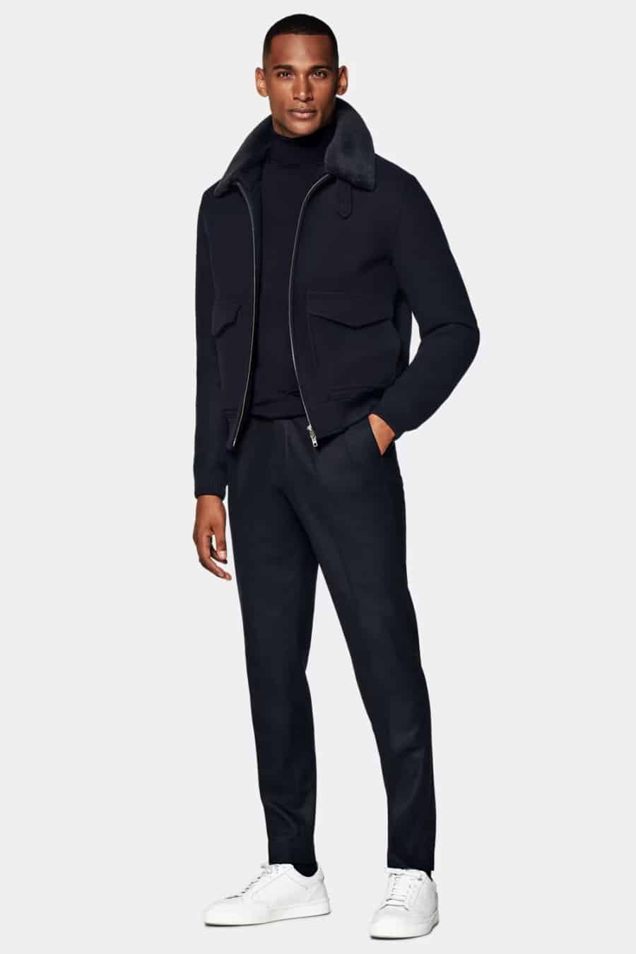 Men's navy wool trousers, navy roll neck jumper, navy shearling collar bomber jacket and white sneakers outfit
