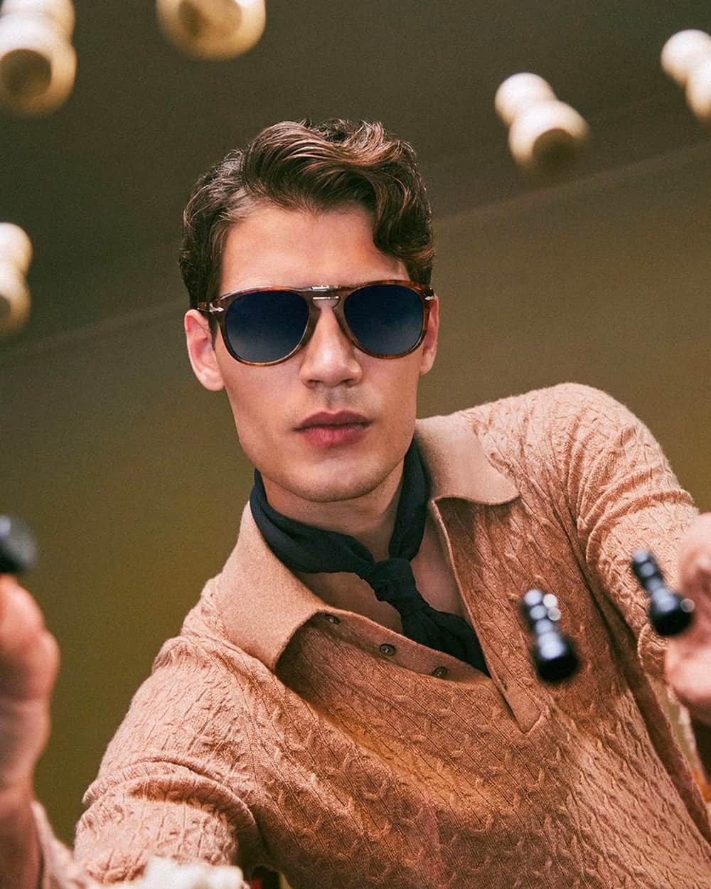 Man wearing foldable Persol keyhole sunglasses with a knitted polo shirt