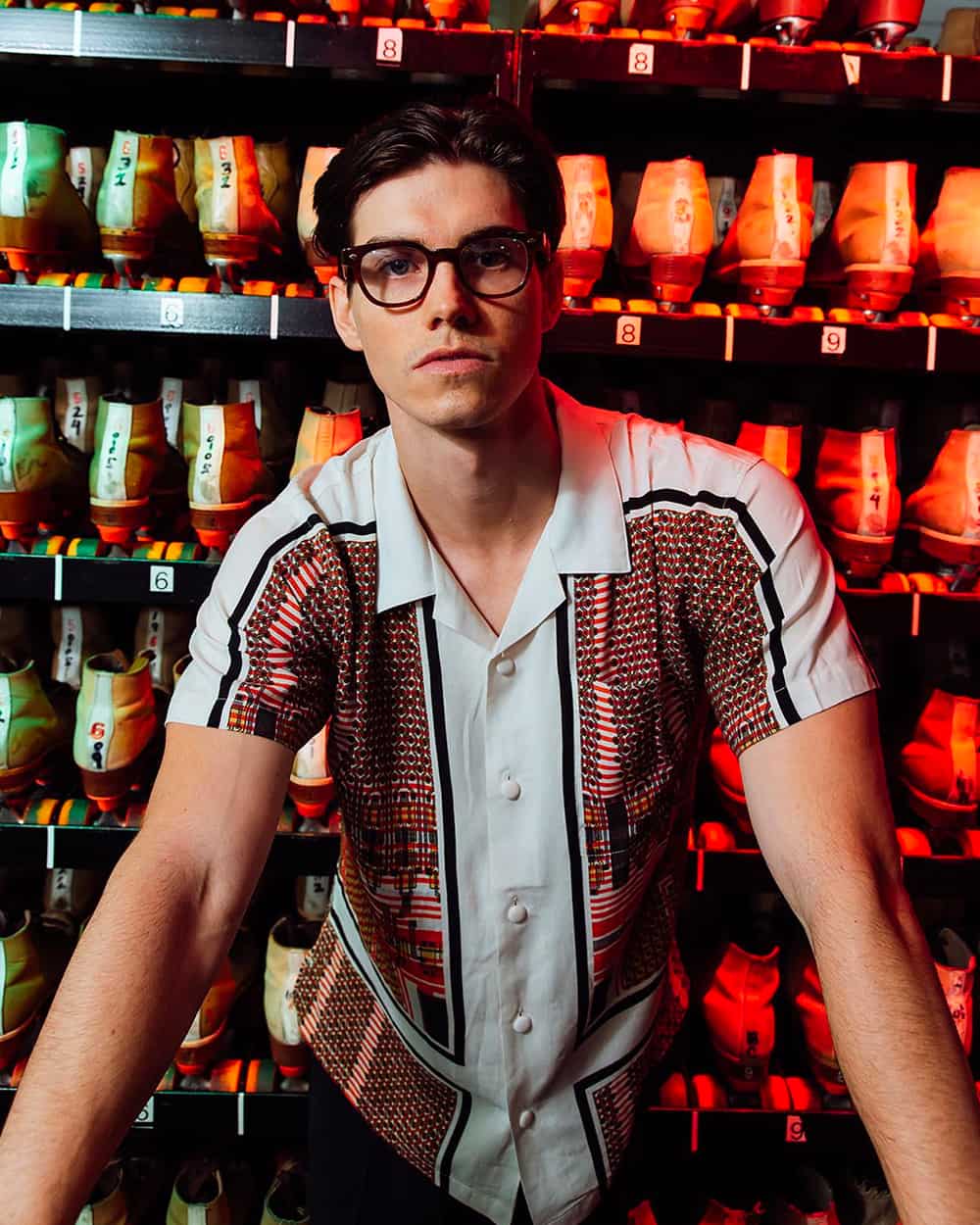 Man wearing patterned camp collar shirt and black oversized round lens spectacles by Garrett Leight