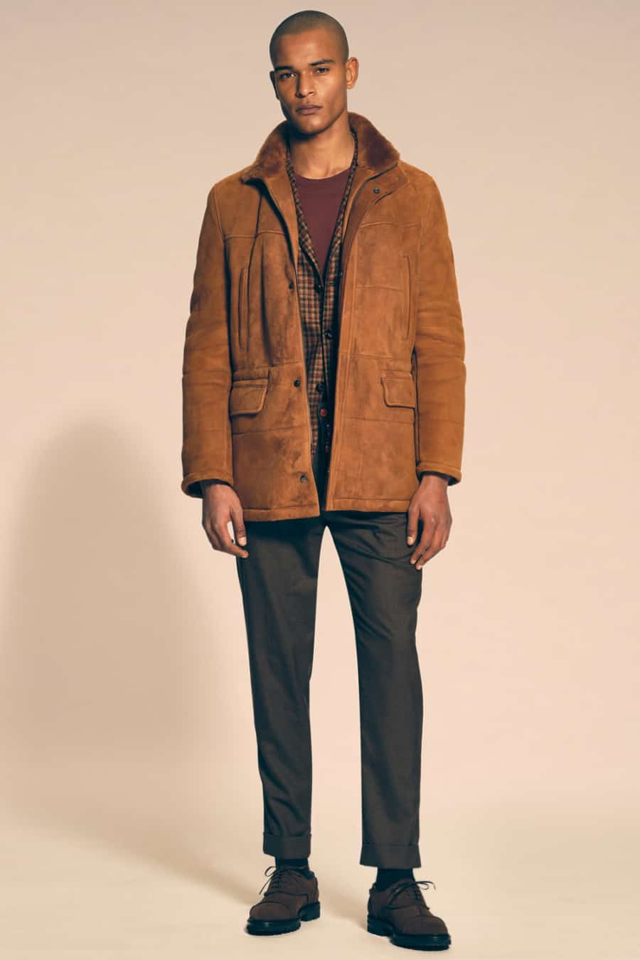 Men's grey pants, burgundy top, brown check blazer, tan sheepskin suede coat and brown suede shoes outfit