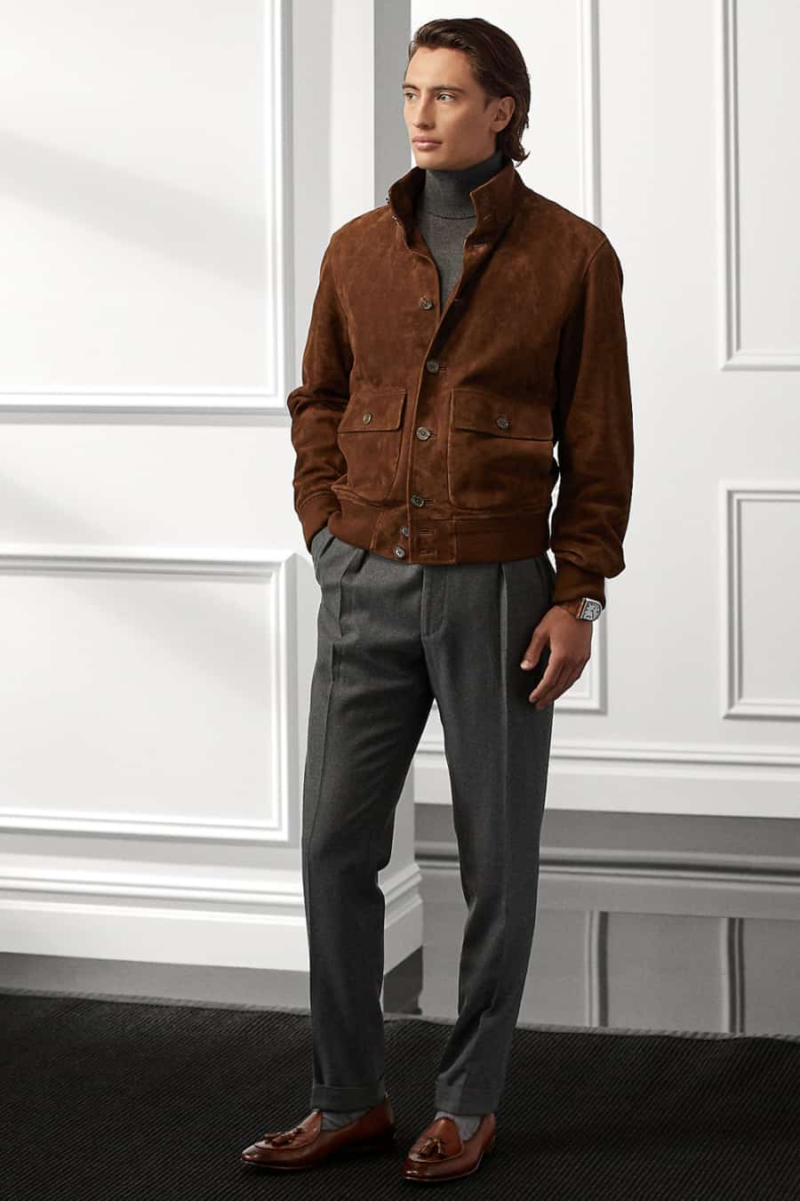 Men's grey wool trousers, charcoal turtleneck, brown suede bomber jacket and brown leather loafers outfit