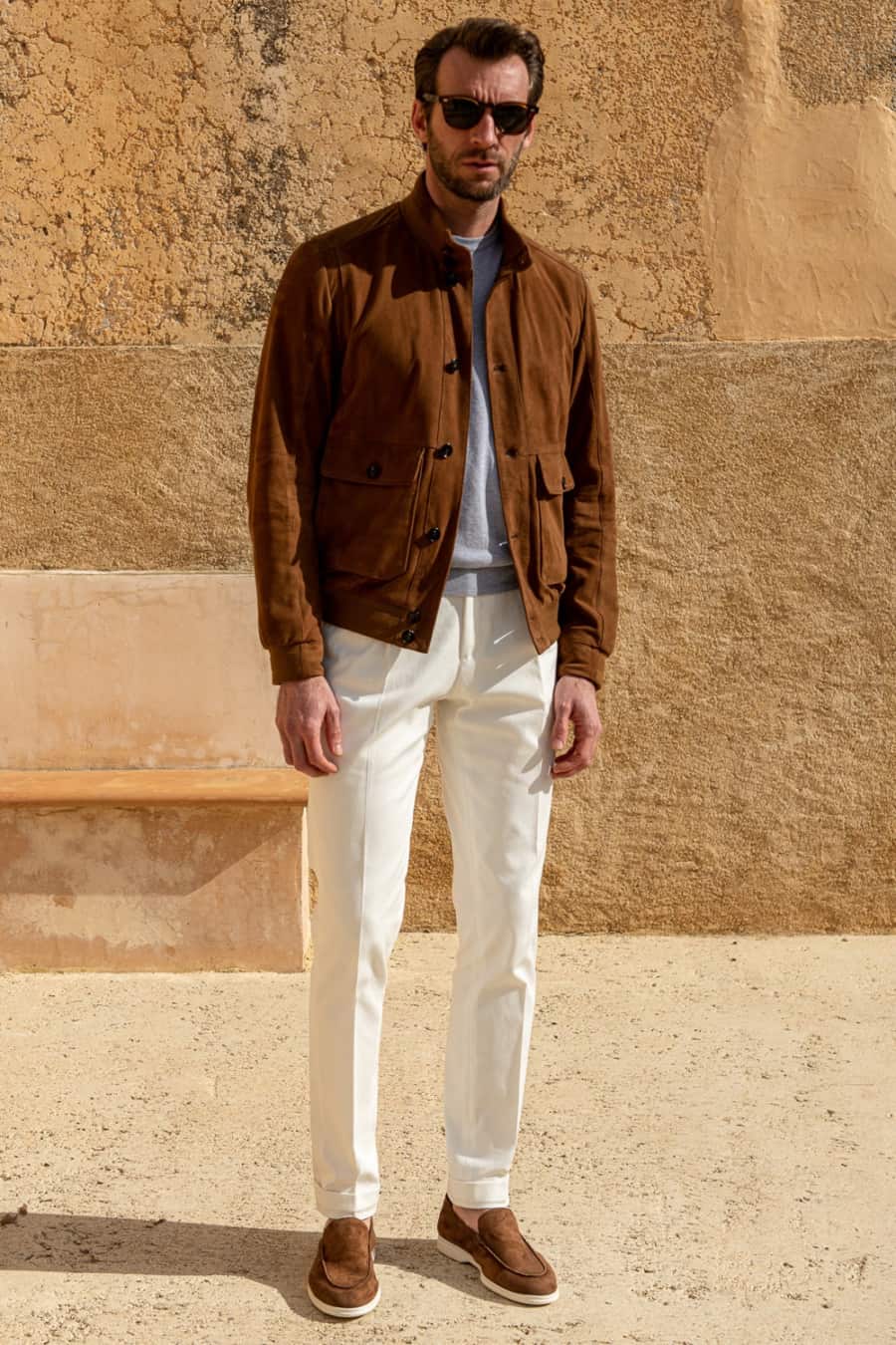 Men's white trousers, grey sweater, brown suede bomber jacket and brown suede loafers outfit