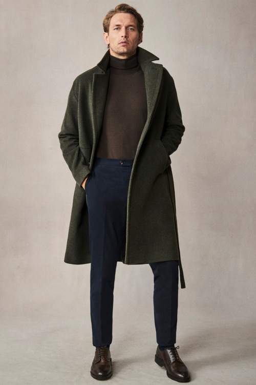 Men's navy trousers, brown turtleneck, green overcoat and brown brogues outfit