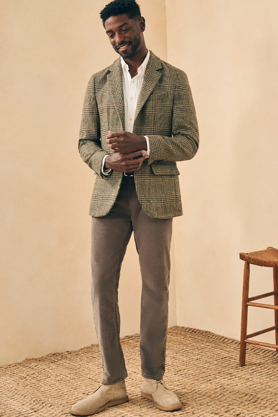 Men's grey chinos, white Oxford shirt, green check tweed blazer and beige suede desert boots business casual outfit