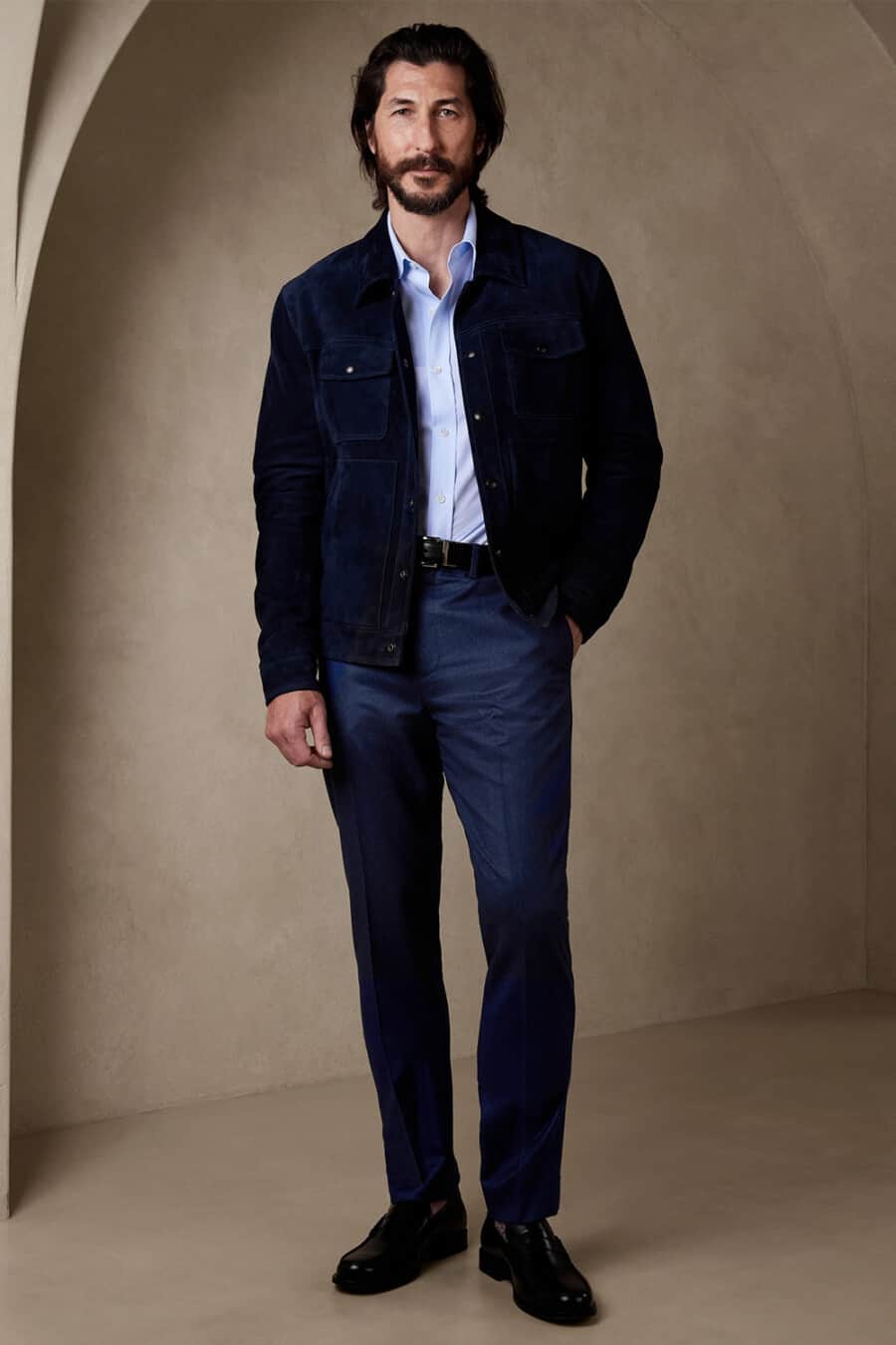 Men's navy tailored pants, light blue shirt, navy suede trucker jacket and black leather penny loafers business casual outfit