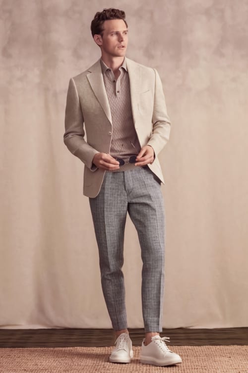 Men's grey trousers, salmon polo shirt, beige blazer and white sneakers outfit