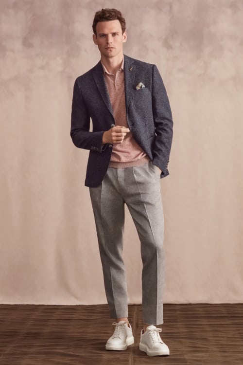 Men's grey trousers, salmon polo shirt, navy blazer and white sneakers outfit