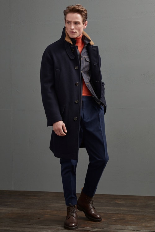 Men's navy trousers, orange roll neck, raw denim jacket, navy overcoat and brown leather boots outfit