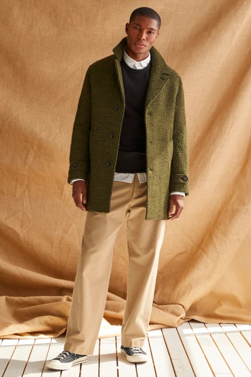 Men's wide leg khaki pants, white shirt, black crew neck sweater, green overcoat and sneakers outfit