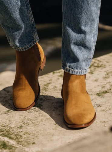 Close up of tan suede Chelsea boots worn with mid wash jeans