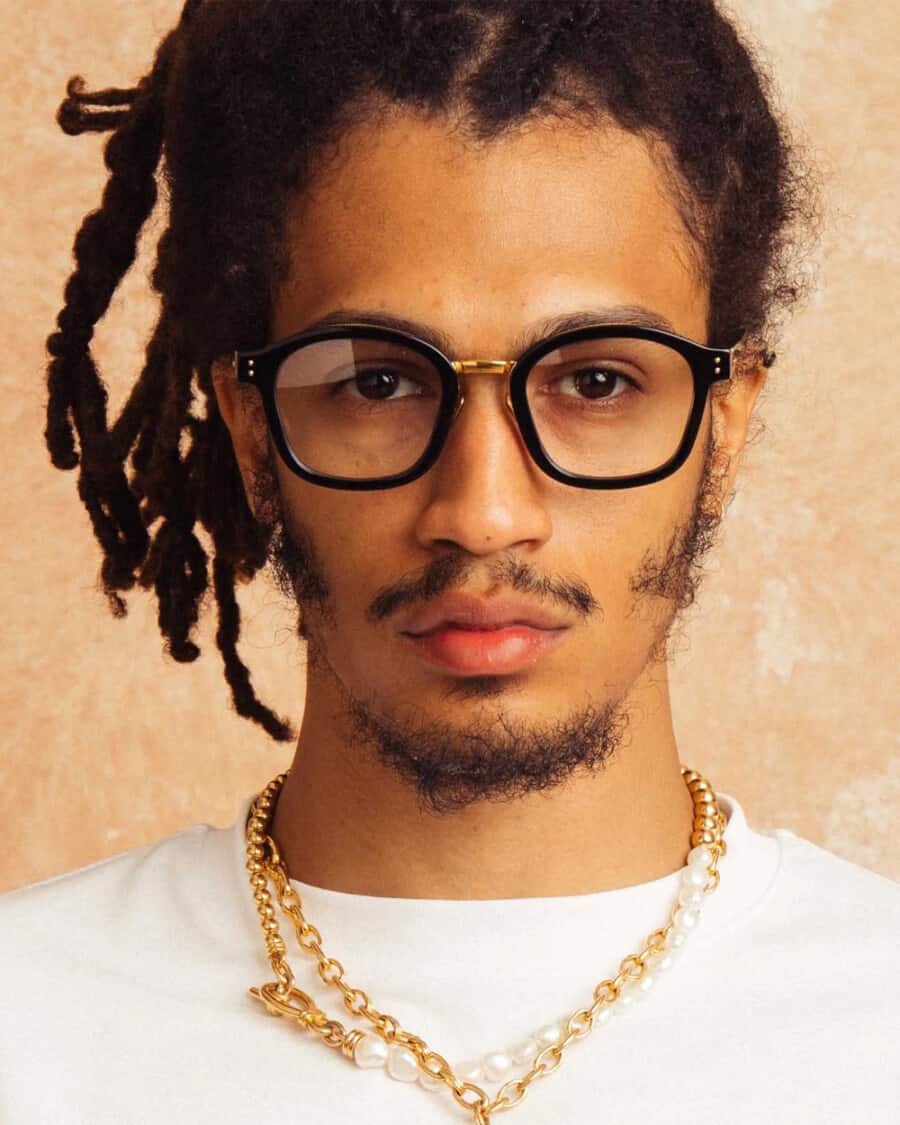 Black man wearing black and gold frame Linda Farrow spectacles