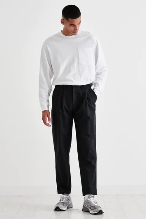 Men's black pleated chinos, white long sleeve top and New Balance sneakers outfit