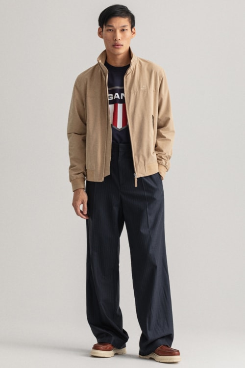Men's wide-leg blue trousers, blue T-shirt, beige Harrington jacket and leather work boots outfit