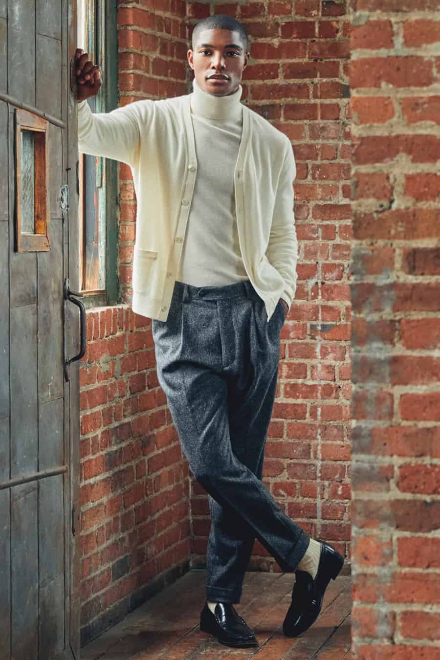 Men's grey wool trousers, off-shit turtleneck, cream cardigan and black loafers outfit