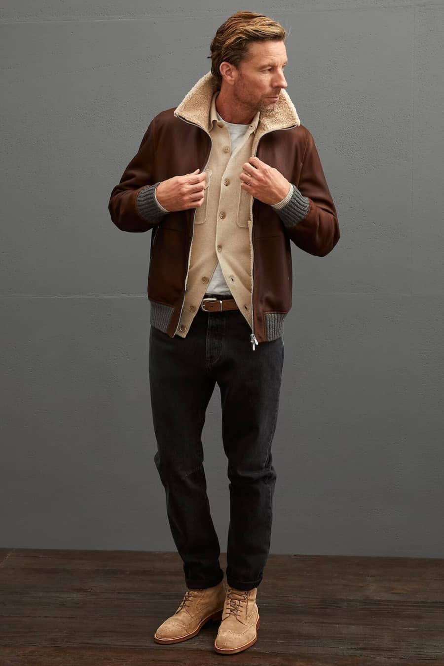 Men's black jeans, white T-shirt, camel cardigan, brown shearling jacket and beige suede boots outfit