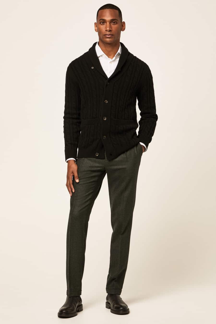 Men's grey trousers, white shirt, black shawl collar cardigan and leather Chelsea boots outfit