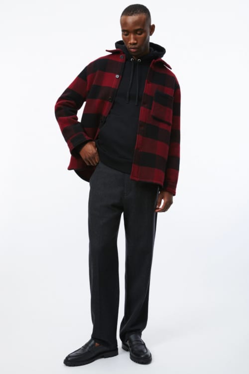 Men's black pants, black hoodie, black and red check flannel shirt and black penny loafers outfit