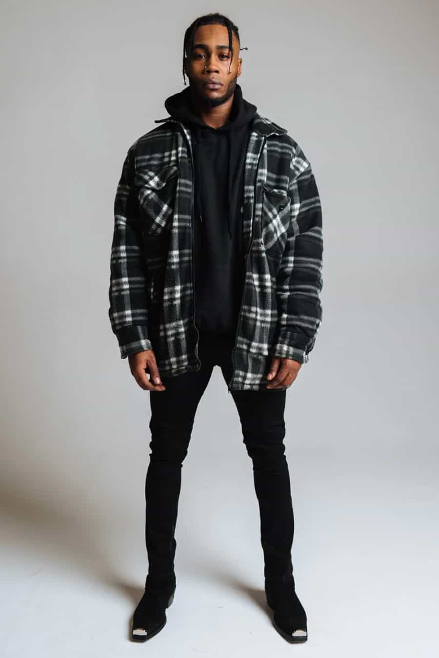 Men's black jeans, black hoodie, black and white checked flannel shirt and black boots outfit