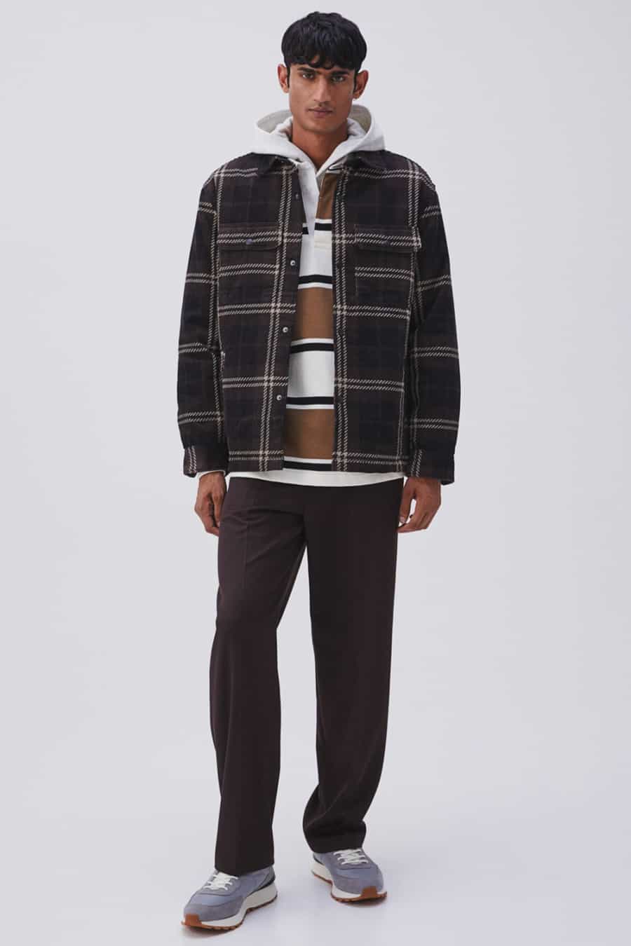 Men's brown trousers, white hoodie, brown rugby top and brown check flannel shirt outfit