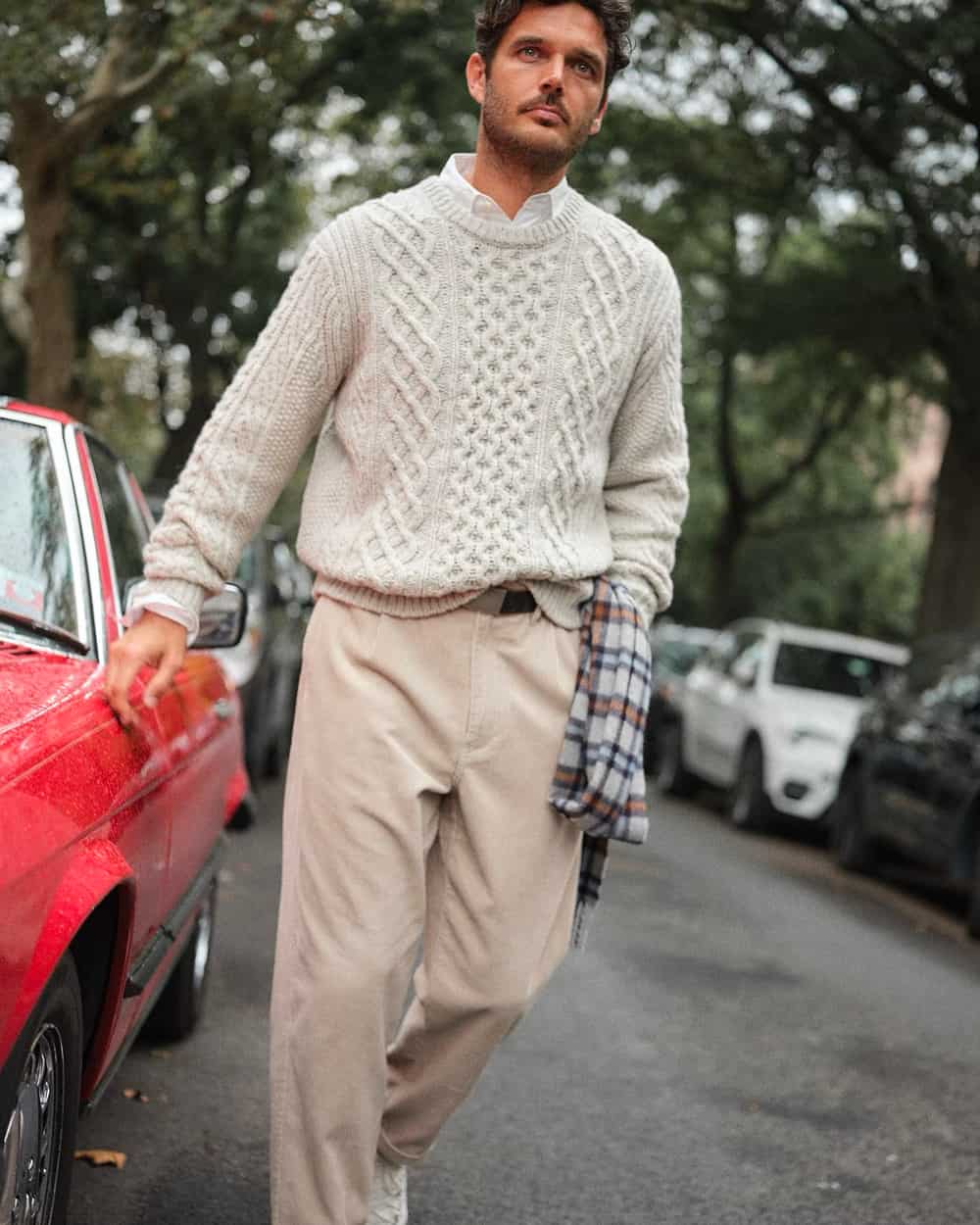 Man wearing Alex Mill loose beige pants, white Oxford shirt and off-white cable knit sweater