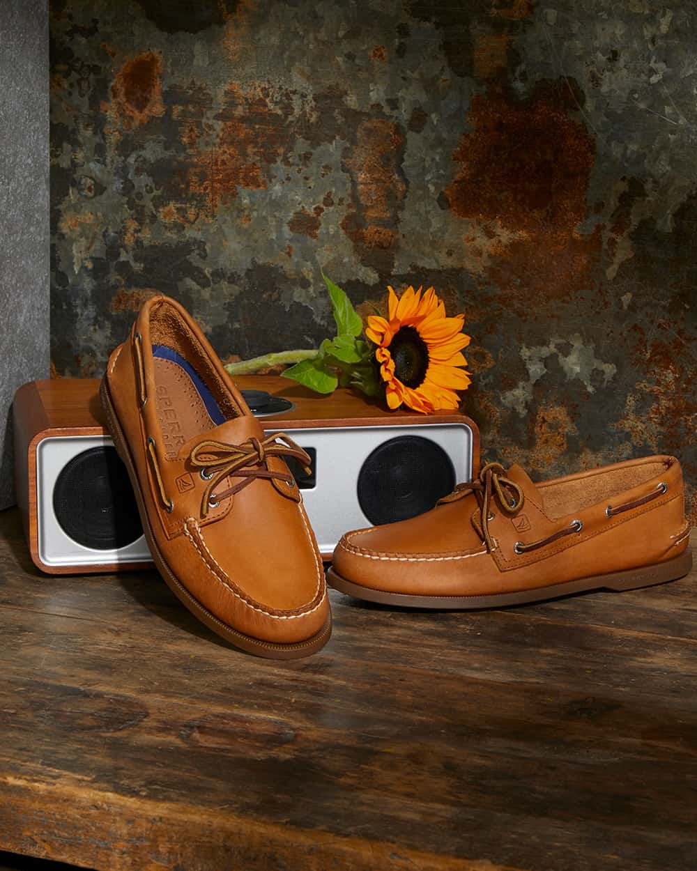 A pair of tan leather Sperry boat shoes with a wooden radio